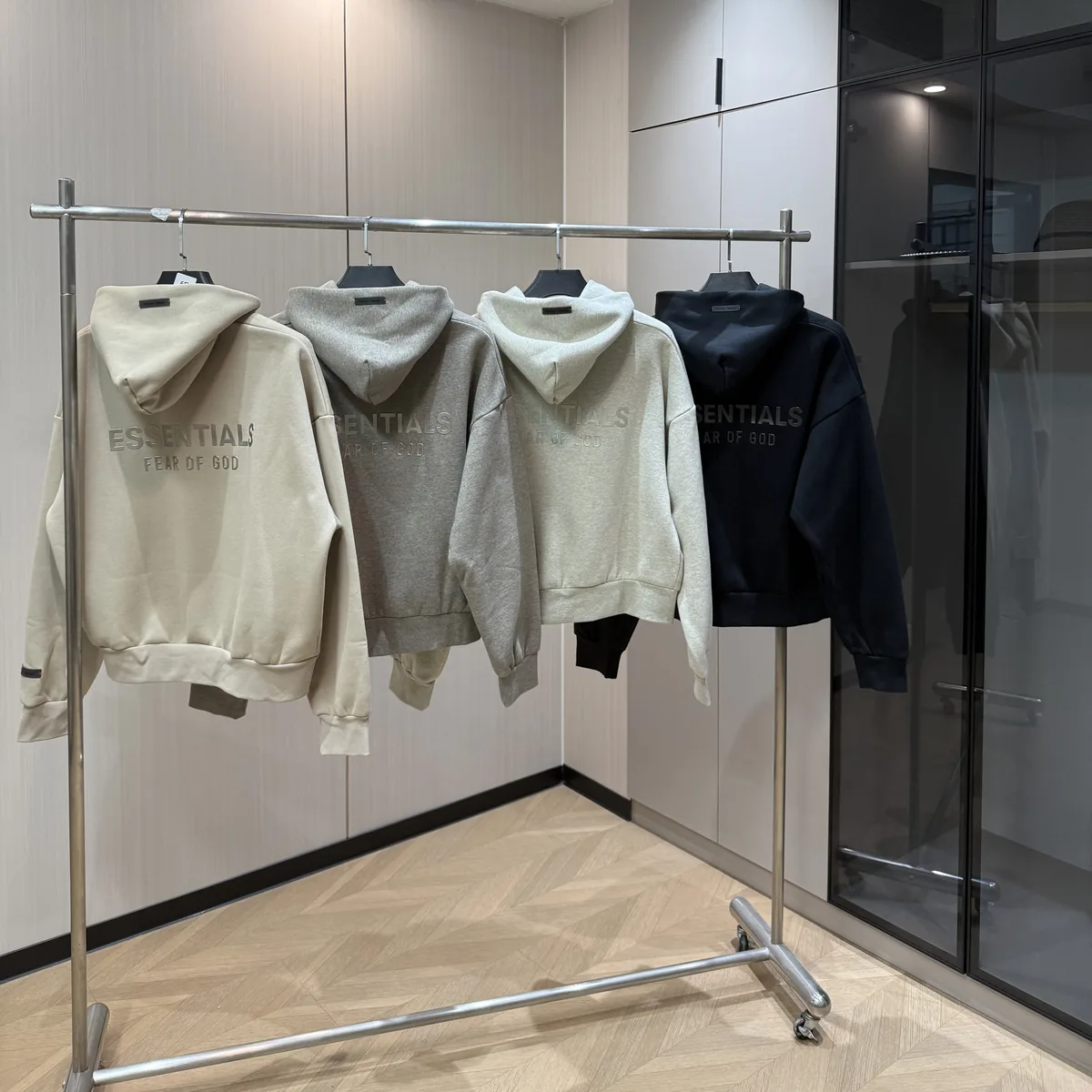 Cuatro hoodies Essentials en percha, vistos de espaldas